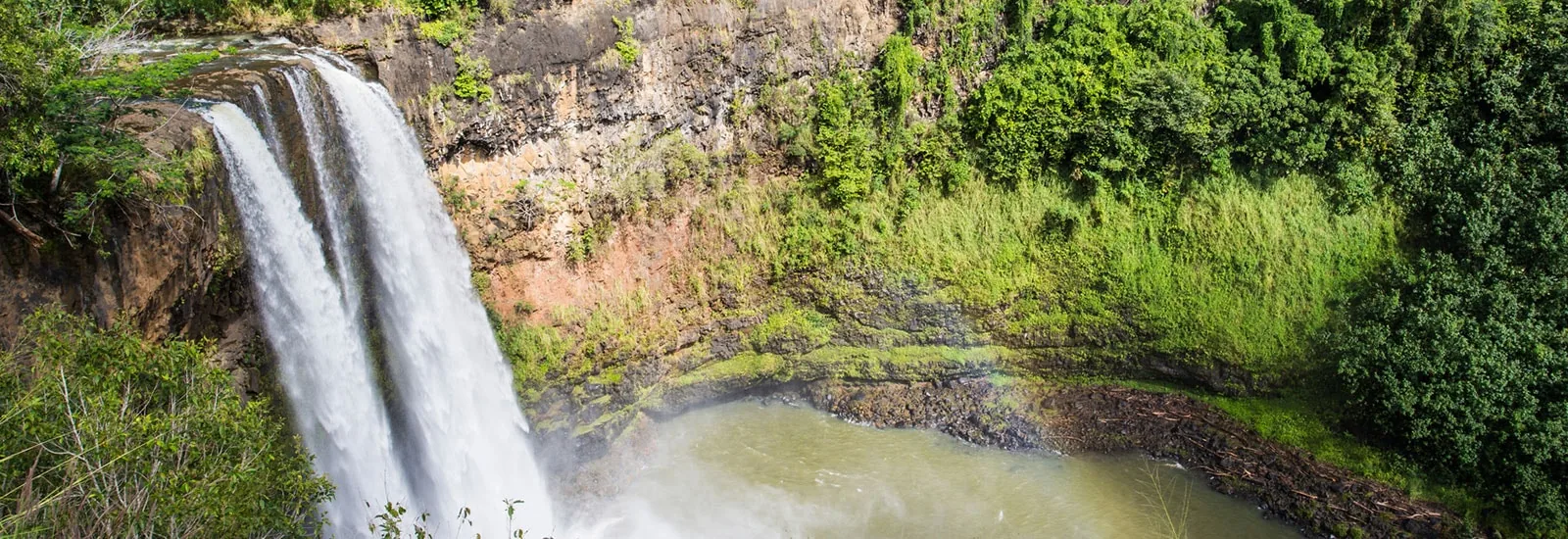 Wailua Falls, a wide twin waterfall dropping into a green pool on Kauai's east side